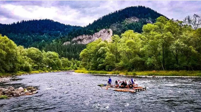 Spływ Dunajcem na tratwie flisackiej w Zakopanem, malowniczy krajobraz górski w tle.