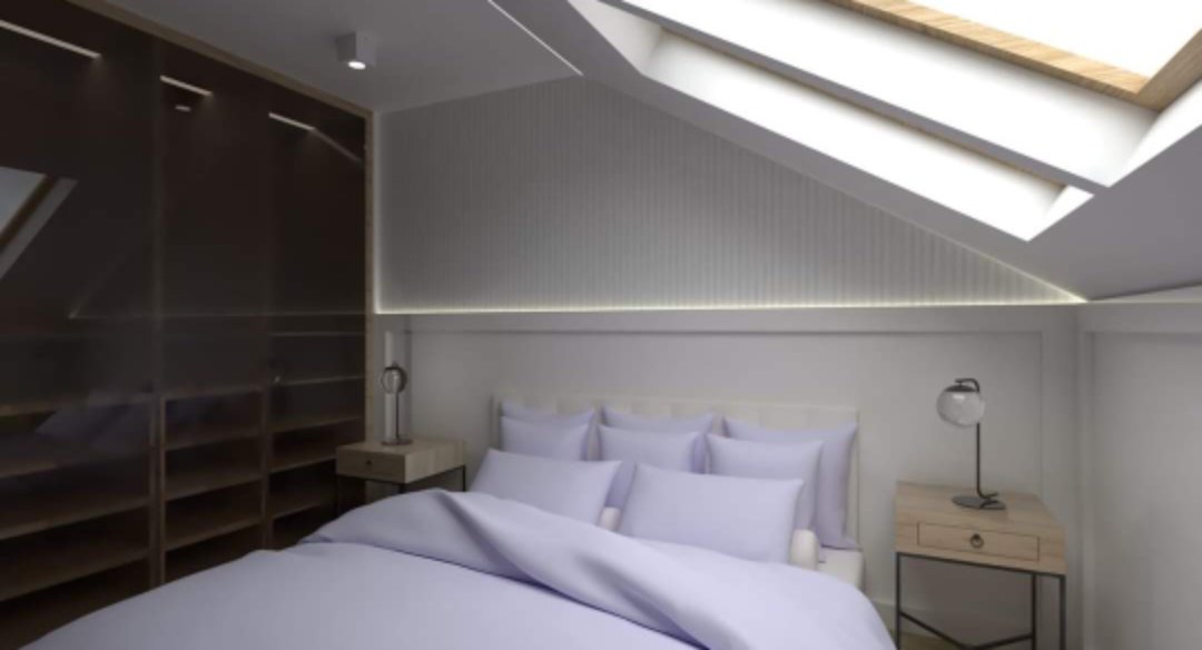 Jasna sypialnia na poddaszu z łóżkiem w pastelowych odcieniach, oknem dachowym i zabudowaną szafą z ciemnego drewna.