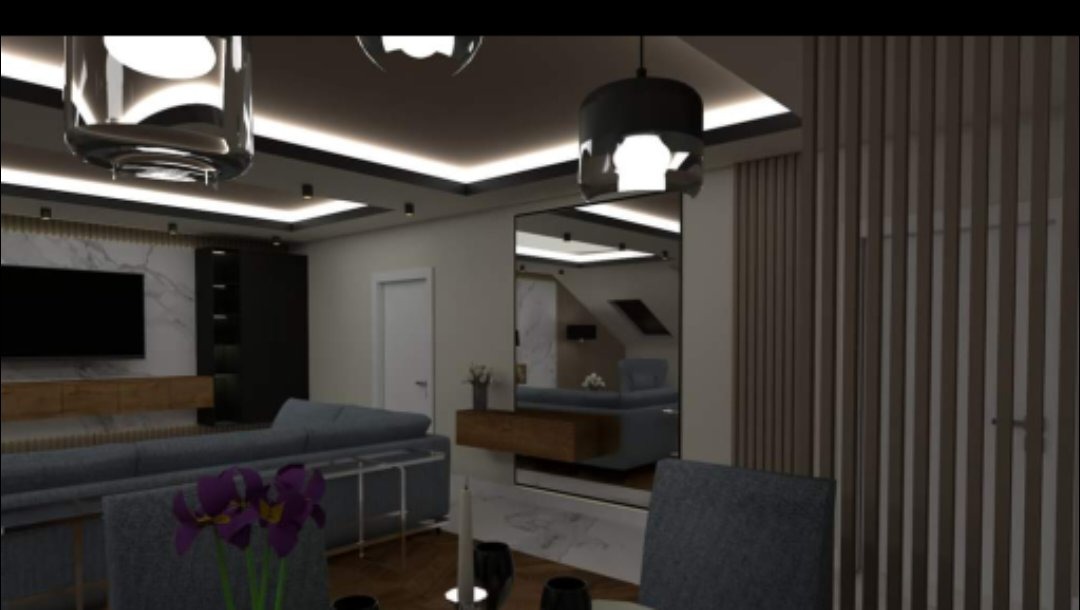 Wizualizacja salonu z szarą sofą, kwiatami na stole i dużym lustrem odbijającym wnętrze poddasza. Nowoczesne oświetlenie sufitowe i dekoracyjne panele ścienne.