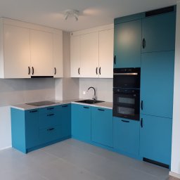 TARAS-MEB Michał Pawlik - Nowoczesna kuchnia z białymi szafkami górnymi i turkusowymi dolnymi, czarne uchwyty, płyta indukcyjna i piekarnik w zabudowie, szara podłoga i ściany.