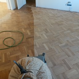 Parkiety Podłogi Układanie Cyklinowanie Renowacja Paweł Zdancewicz - Parkiet ułożony w jodełkę, częściowo po procesie szlifowania, widoczna maszyna do cyklinowania i zielony przewód.