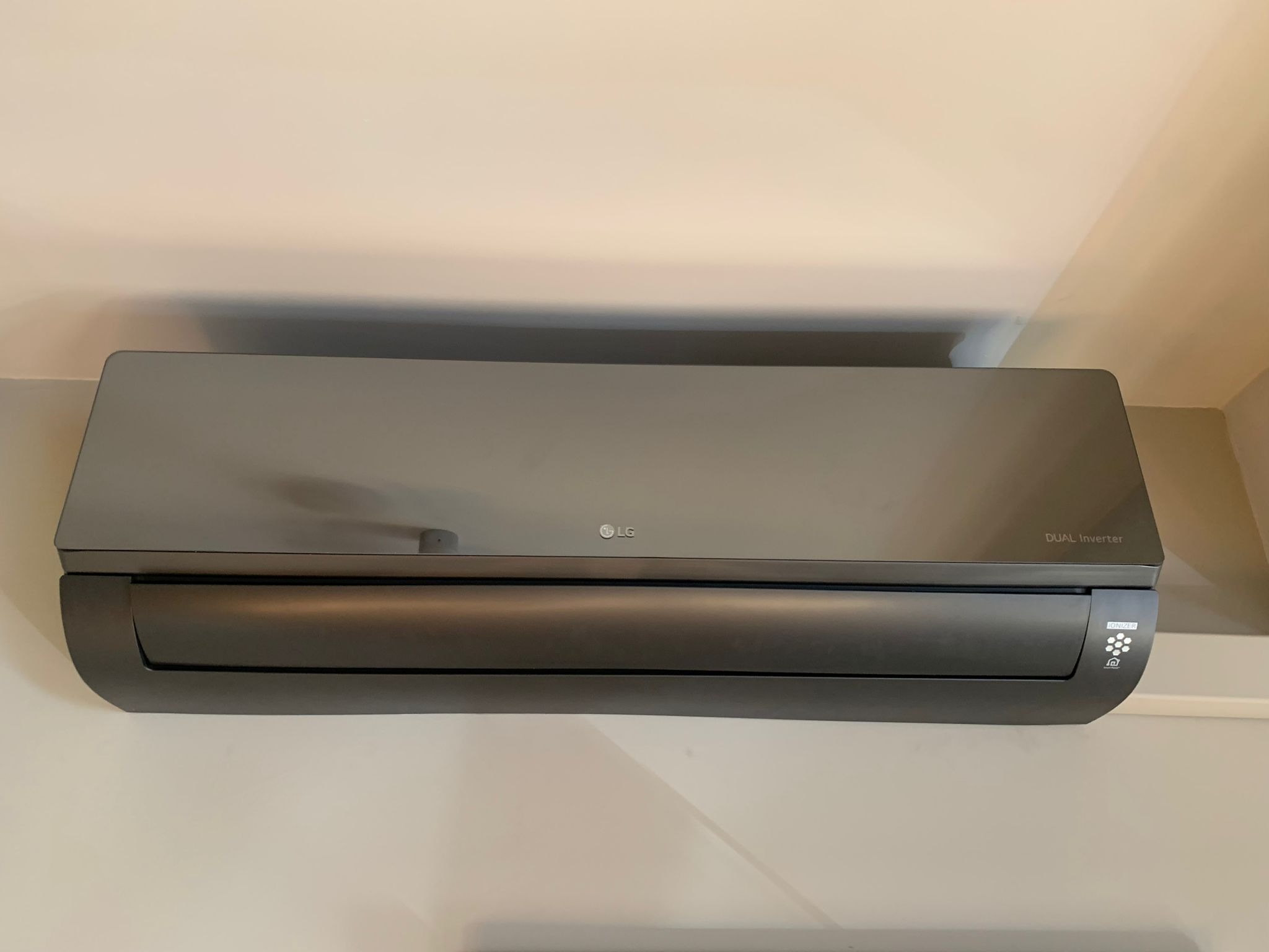 Czarny klimatyzator LG Dual Inverter zamontowany na jasnej ścianie w pomieszczeniu.