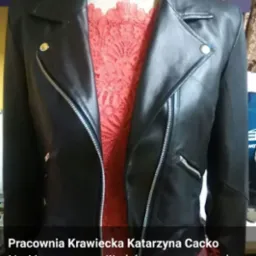 Czarna skórzana ramoneska na manekinie, widoczna z przodu, z rozpiętym zamkiem błyskawicznym, ukazująca koronkową bluzkę pod spodem.