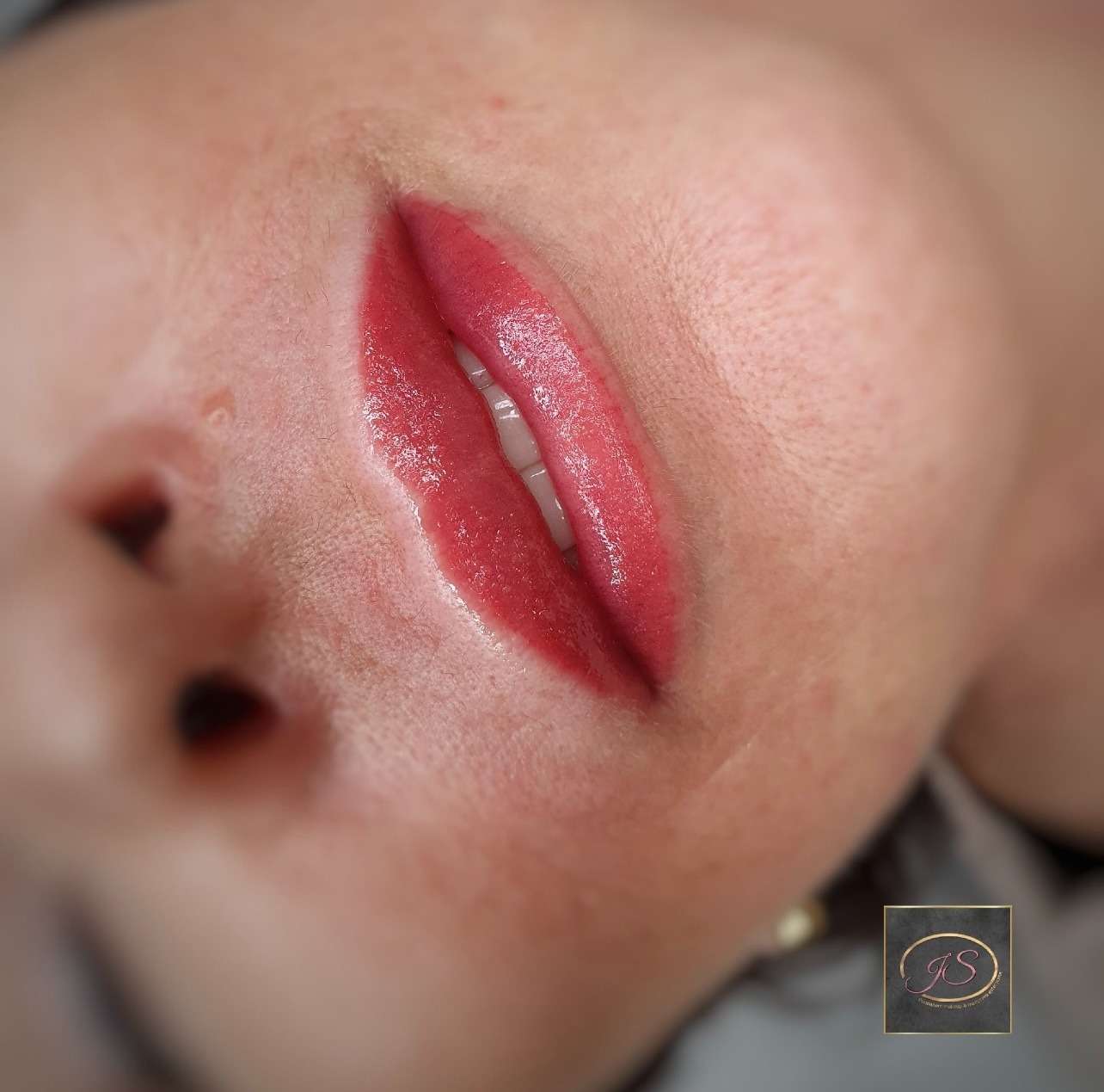 Zbliżenie na kobiece usta po zabiegu pigmentacji, widoczne delikatne zaczerwienienie skóry wokół ust, podkreślony kontur i intensywny kolor czerwieni.
