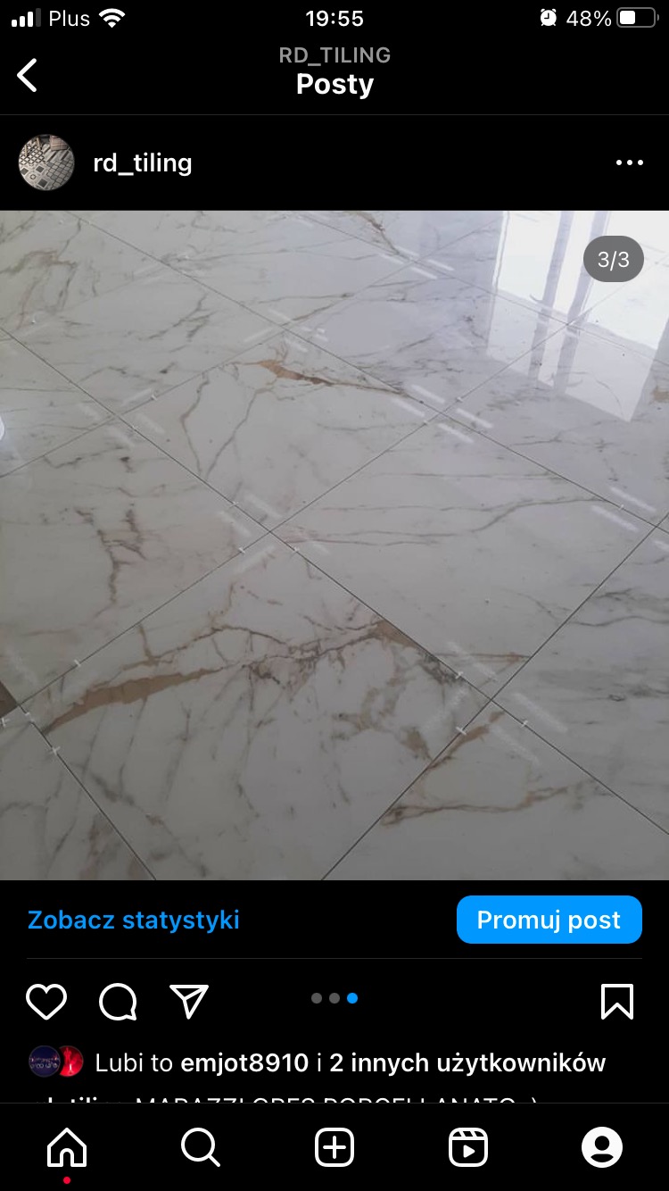 Białe płytki podłogowe imitujące marmur z delikatnymi złotymi żyłkami, ułożone w kwadraty, z widocznymi krzyżykami dystansowymi w spoinach.