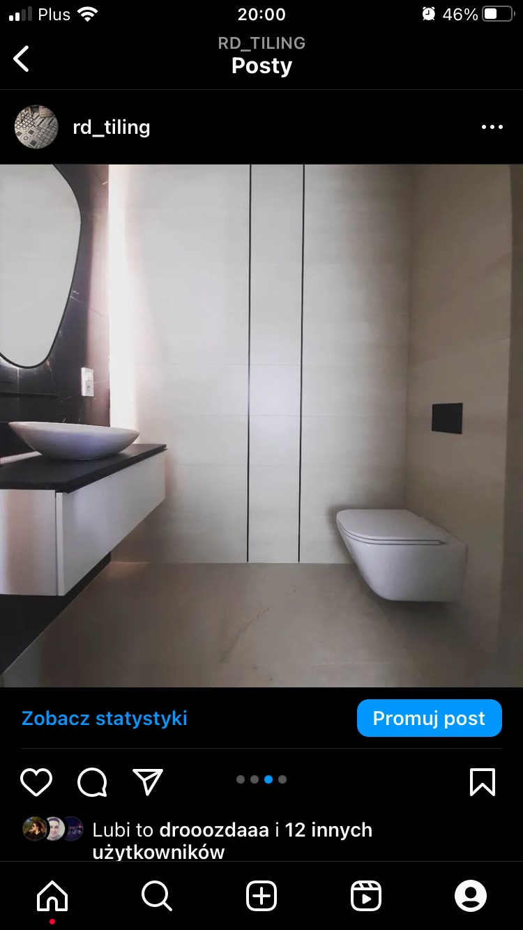 Nowoczesna łazienka z umywalką nablatową na białej szafce, wiszącą toaletą i jasnymi płytkami z czarnymi akcentami.