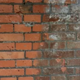 Ceglana ściana w trakcie czyszczenia, z wyraźnym podziałem na obszar czysty i zabrudzony, ukazując efekt renowacji.