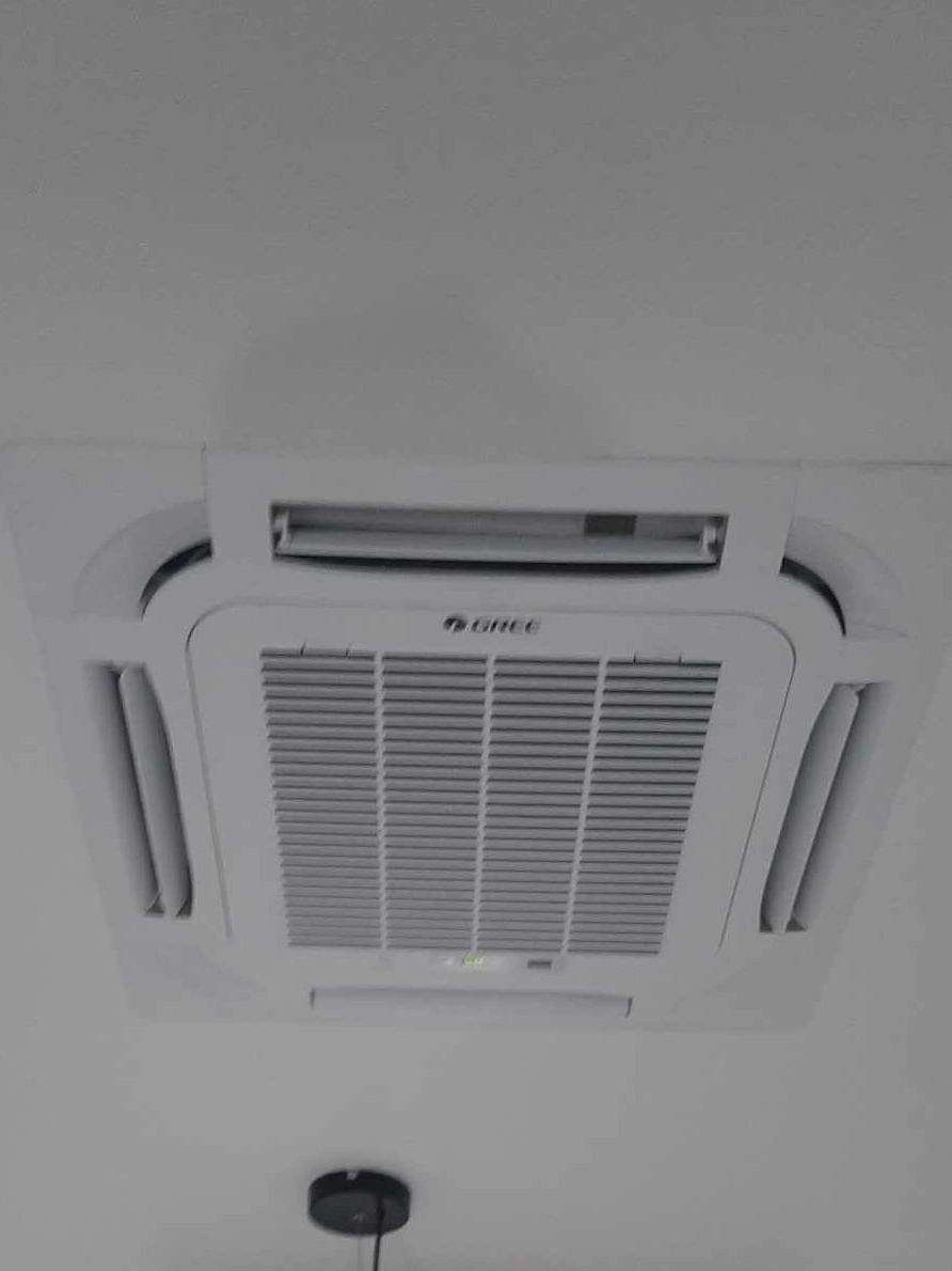 Kasetonowa jednostka klimatyzacji marki Gree zamontowana na suficie w biurze w Legionowie, widok z dołu.