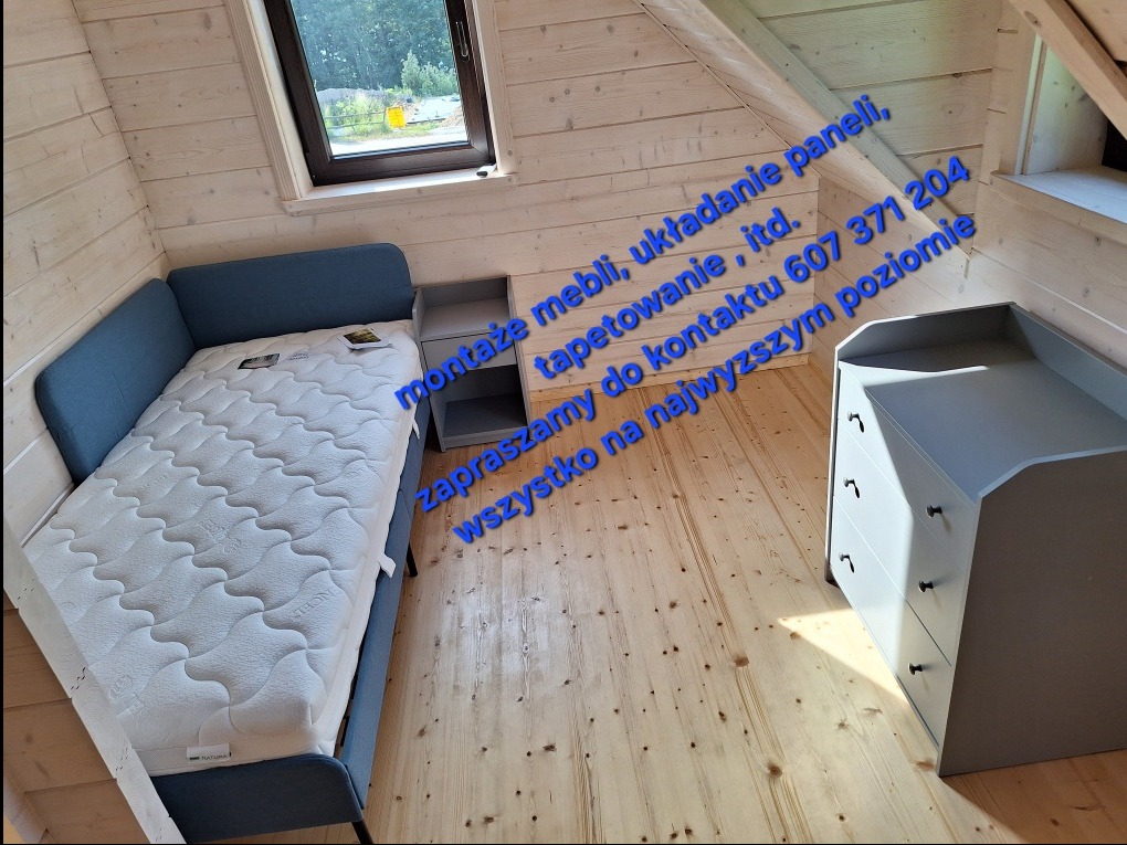 Pokój na poddaszu z drewnianą boazerią: szare meble (łóżko, szafka nocna, komoda), okno dachowe. Widoczna podłoga z jasnych paneli. Umeblowane wnętrze.