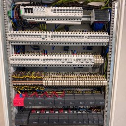 ElektroGriner - Rozdzielnica elektryczna z modułami, bezpiecznikami i okablowaniem wewnątrz szafy. Widoczne elementy automatyki i sterowania.