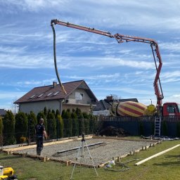 F.H.U. SOWA Joanna Sowa - Betonowanie fundamentów pod kostkę brukową w Ożarach z użyciem pompy do betonu, widoczni pracownicy i przygotowany teren.