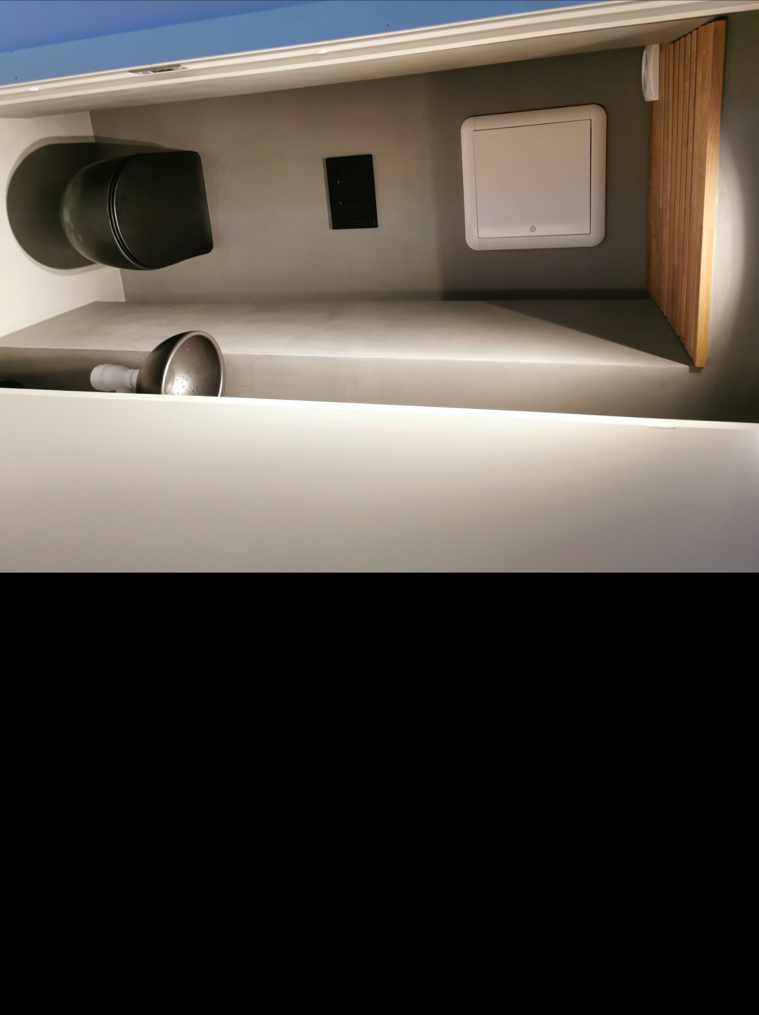 Nowoczesna szara łazienka z podwieszaną toaletą, umywalką i drewnianymi panelami ściennymi, widok z dołu.