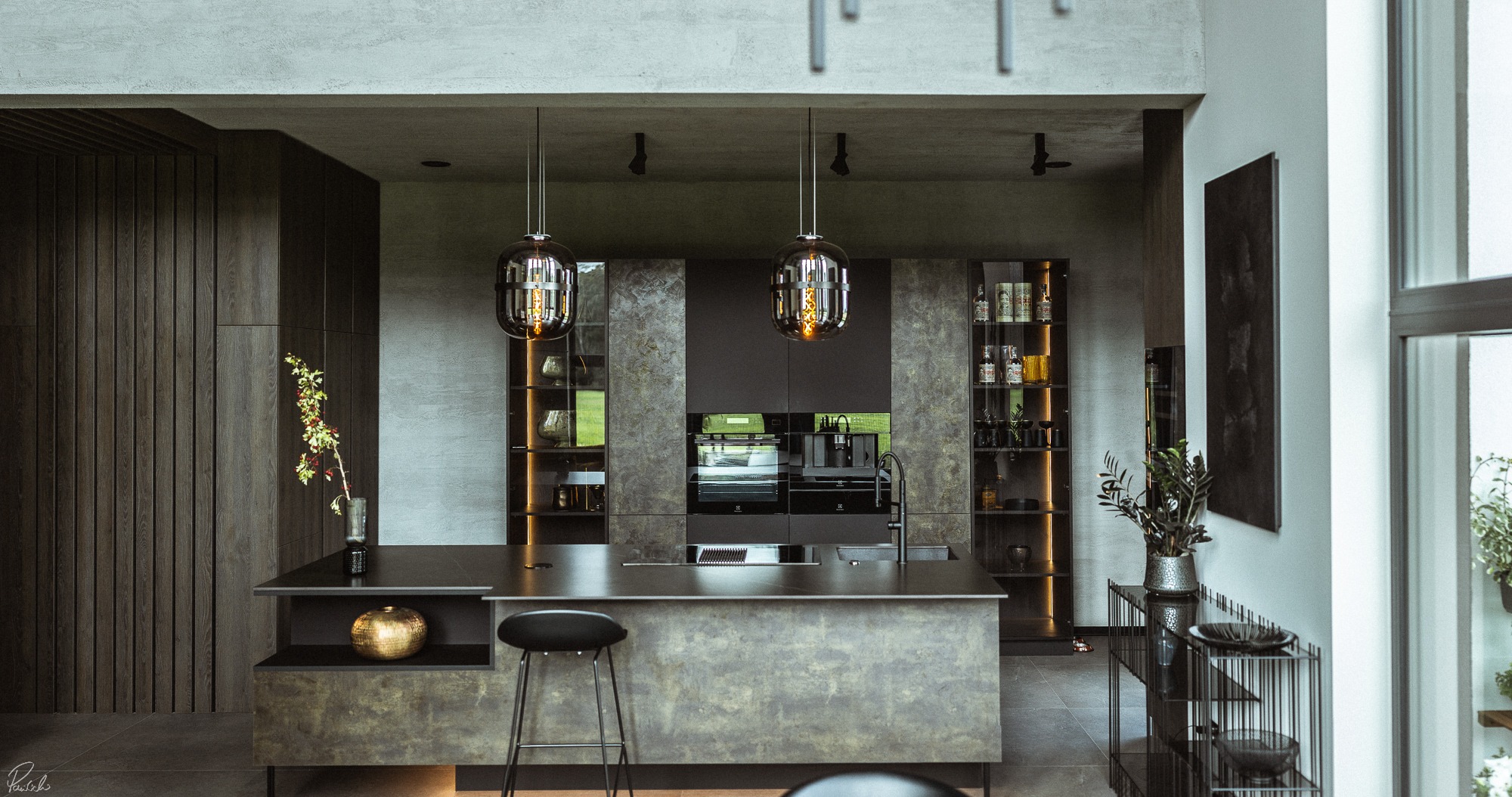 Nowoczesna kuchnia z wyspą, oświetlona wiszącymi lampami, z ciemnymi drewnianymi elementami i dekoracjami, takimi jak złota kula i gałązka w wazonie. Widoczne zabudowane sprzęty AGD.