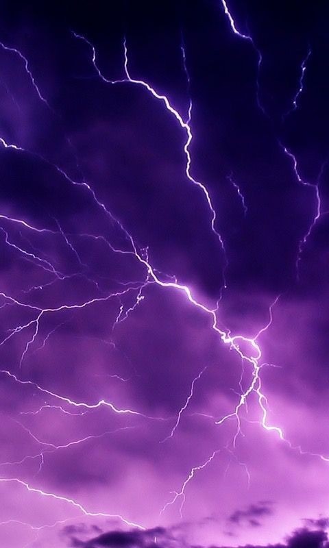 Intensywne fioletowe niebo rozświetlone przez liczne rozgałęzione błyskawice, tworzące dramatyczny i energetyczny krajobraz.
