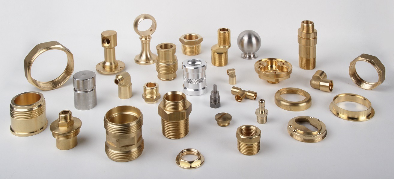 Zestaw precyzyjnie wykonanych, różnorodnych metalowych elementów i złączek z mosiądzu i stali nierdzewnej, ułożonych na białym tle, prezentujących gwintowane końcówki, kolanka i pierścienie.