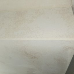 Raz a Dobrze. - Jasna, beżowa ściana wykończona płytkami, z widoczną fugą. Płytki imitują naturalny kamień, tworząc subtelny wzór. Minimalistyczny detal wykończenia wnętrza.