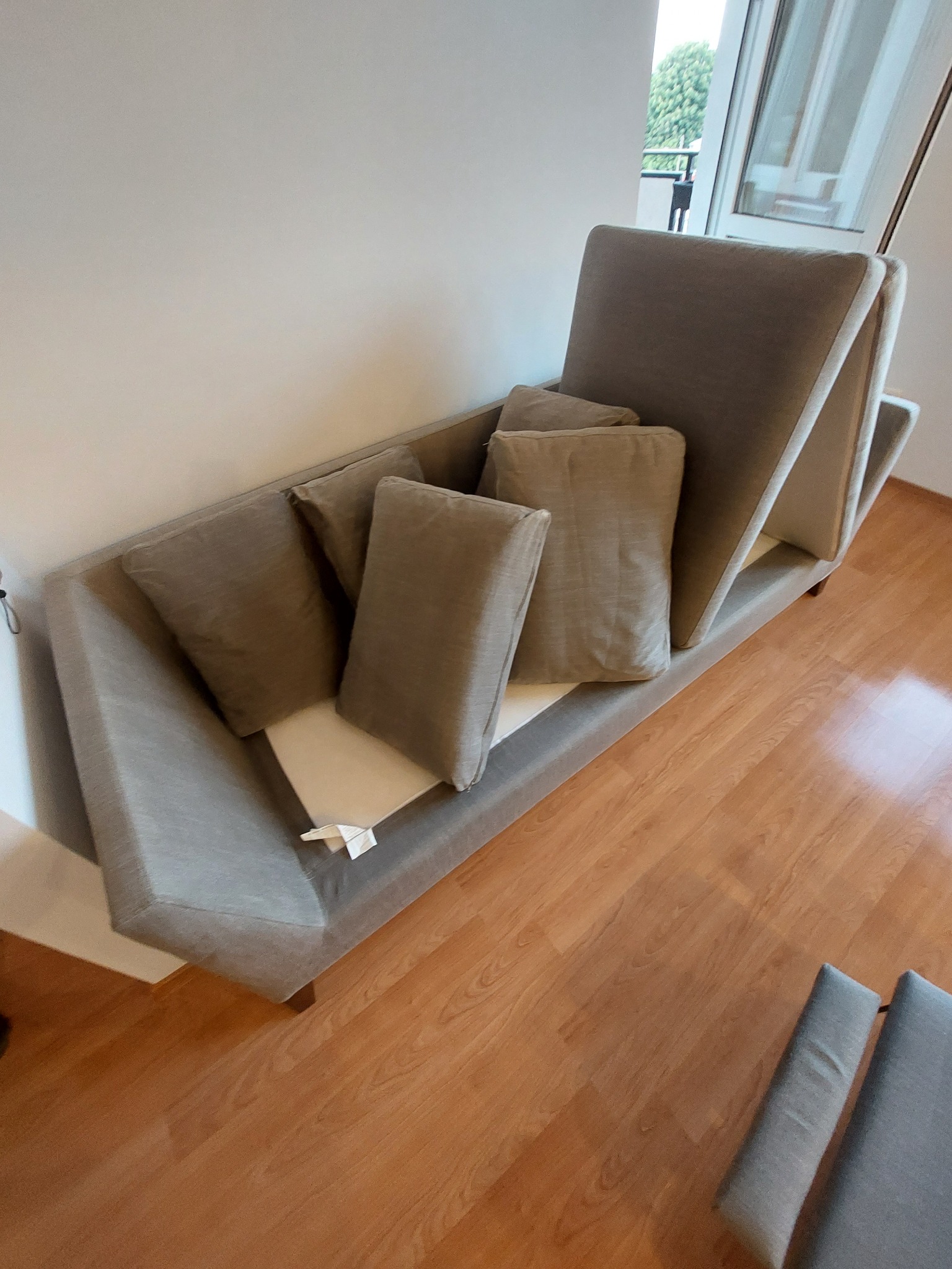 Szary, modułowy narożnik z poduszkami w dziennym świetle, widok z góry, na podłodze panele.