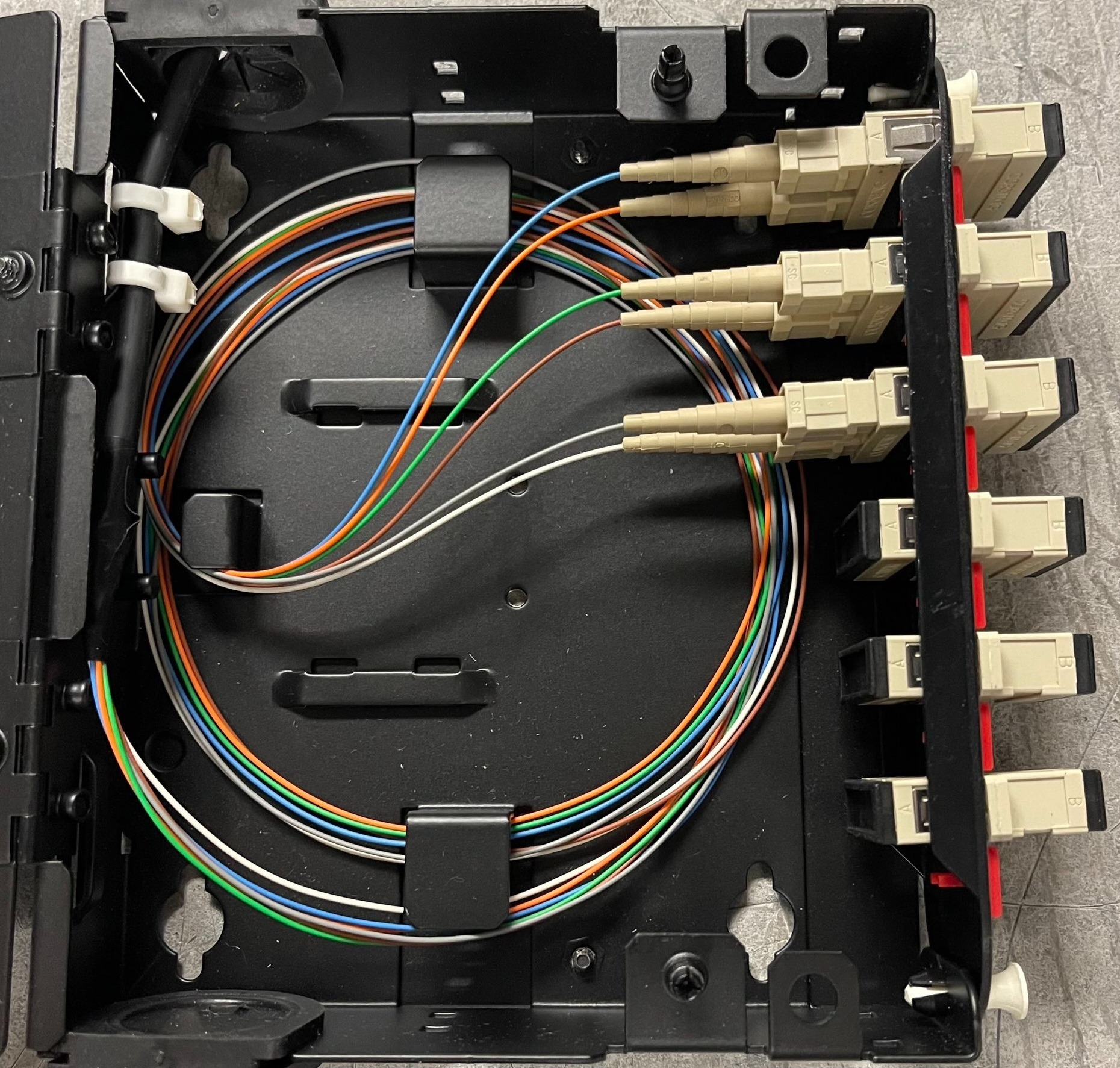 Panel krosowy światłowodowy z uporządkowanymi, kolorowymi kablami światłowodowymi i beżowymi złączami SC, widoczne oznaczenia A i B na złączach.
