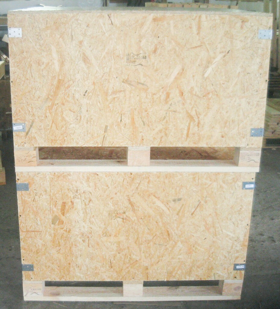 Duża, drewniana skrzynia transportowa z płyty OSB, wzmocniona metalowymi narożnikami, ustawiona na palecie.