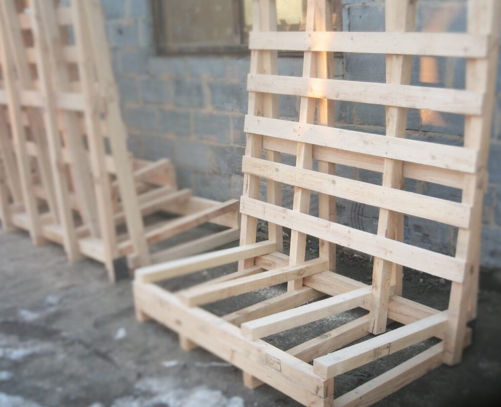 Surowe drewniane palety ułożone na zewnątrz, z lekkim efektem bokeh na tle szarego muru.