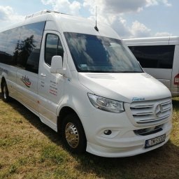 Zalvis PRZEWOZY DO NIEMIEC, BELGII, HOLANDII, SZWAJACARII - Biały bus Mercedes Sprinter z chromowanymi felgami na trawiastym terenie, widoczny numer rejestracyjny LTM 51008, logo 'zalvis' i 'mercus' oraz dane kontaktowe firmy.