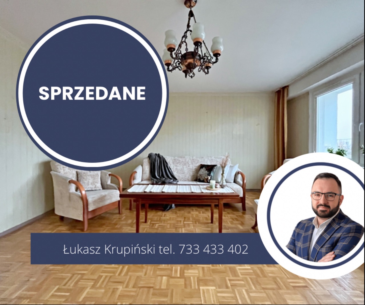 Salon z drewnianą podłogą, sofą, fotelem i żyrandolem. Na zdjęciu widoczny napis 'Sprzedane' oraz dane kontaktowe pośrednika.