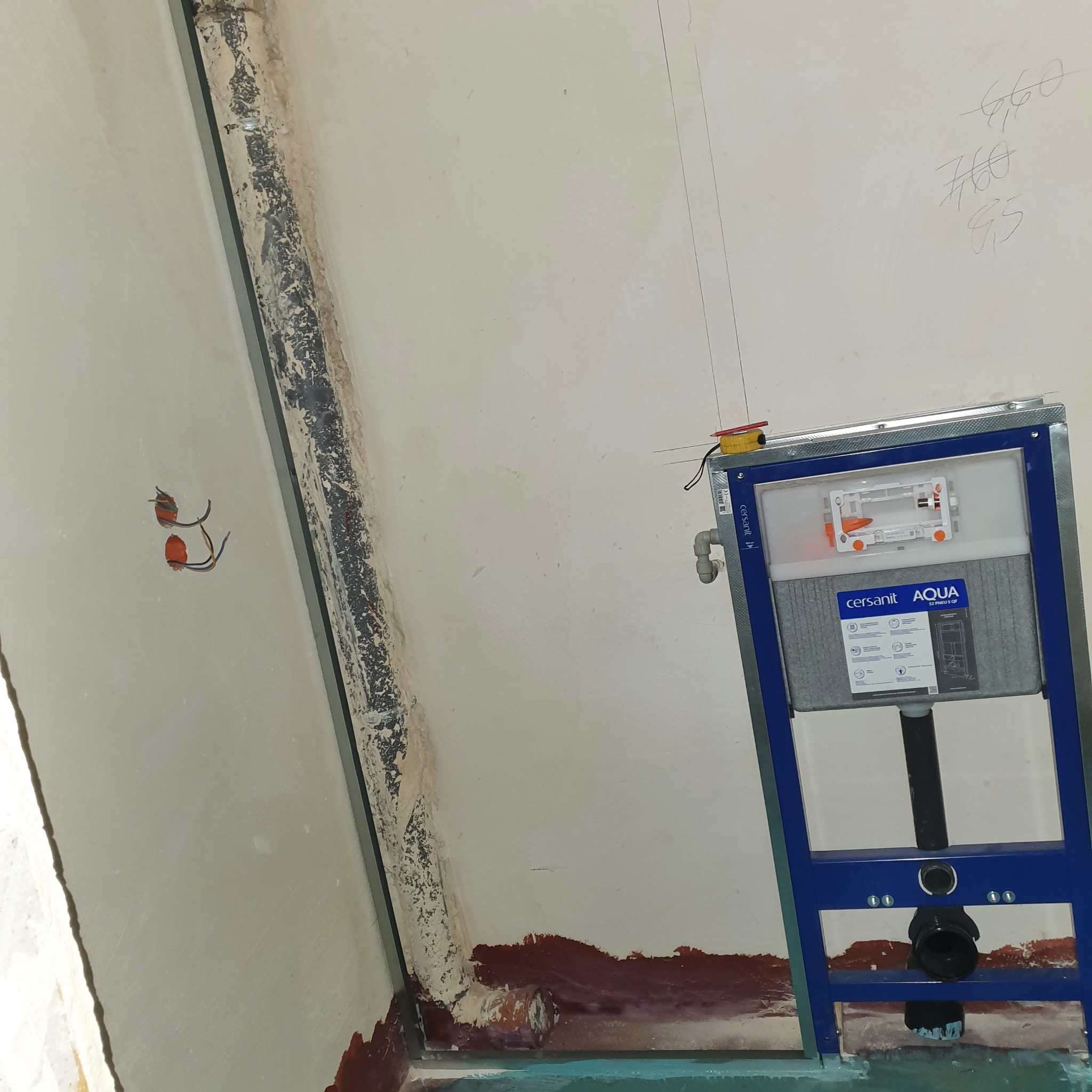 Stelaż podtynkowy Cersanit Aqua zamontowany w łazience w trakcie prac wykończeniowych, widoczne wystające kable elektryczne i ślady po starych instalacjach na ścianie.