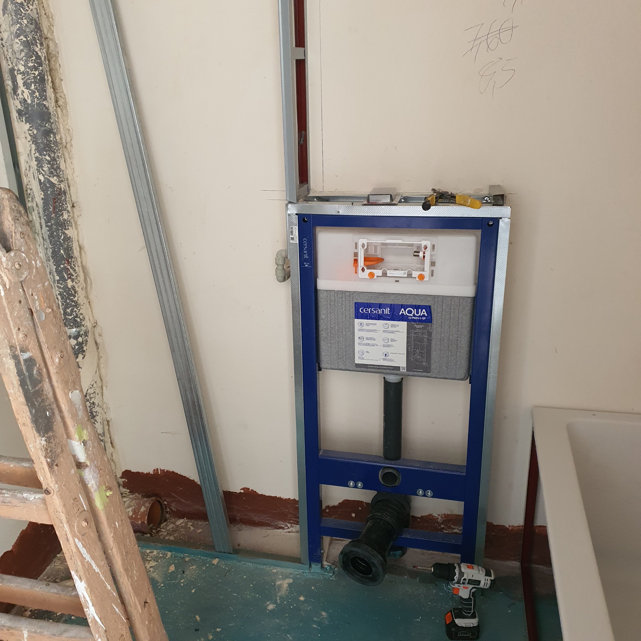 Stelaż podtynkowy Cersanit Aqua zamontowany w trakcie remontu łazienki, widoczne profile metalowe, drabina malarska i wiertarka.