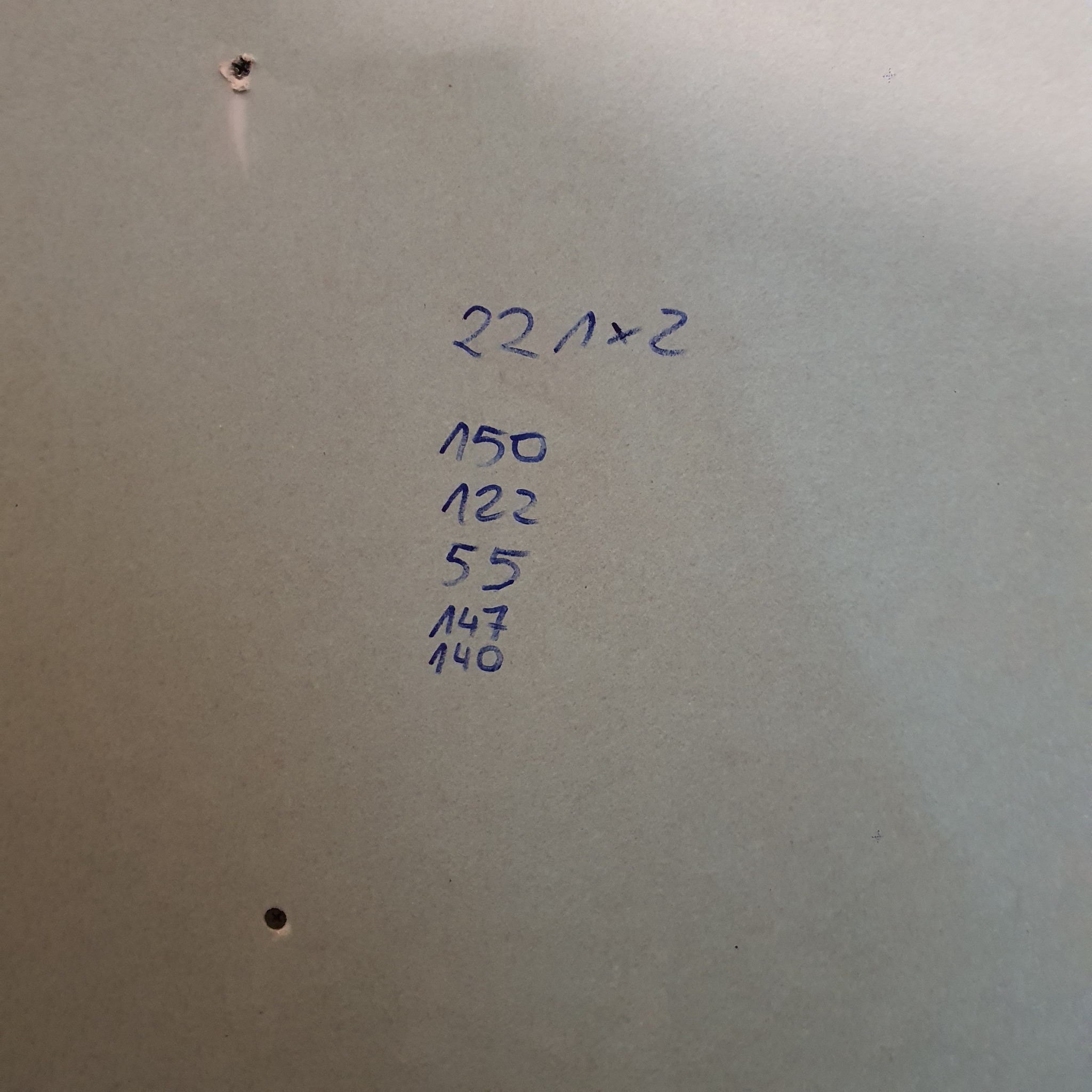 Płyta karton gips z odręcznymi notatkami w kolorze niebieskim zawierającymi wymiary, widoczne dwa otwory po wkrętach.