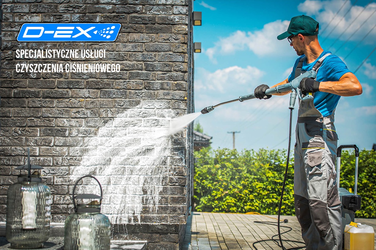 Mężczyzna w okularach i czapce czyści ciśnieniowo ceglaną elewację, widoczny efekt czyszczenia, na pierwszym planie ozdobne lampiony, w tle błękitne niebo.