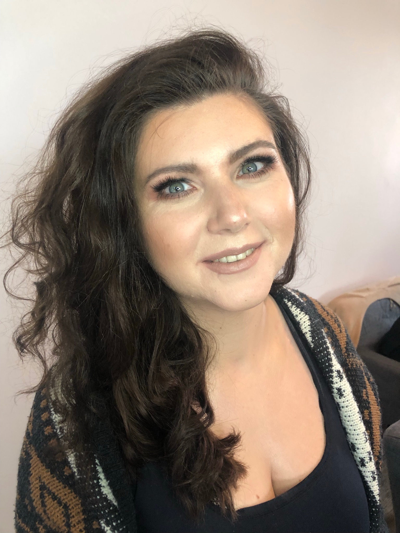 Portret uśmiechniętej kobiety z profesjonalnym makijażem: delikatny makijaż oczu, podkreślone kości policzkowe, naturalne usta.