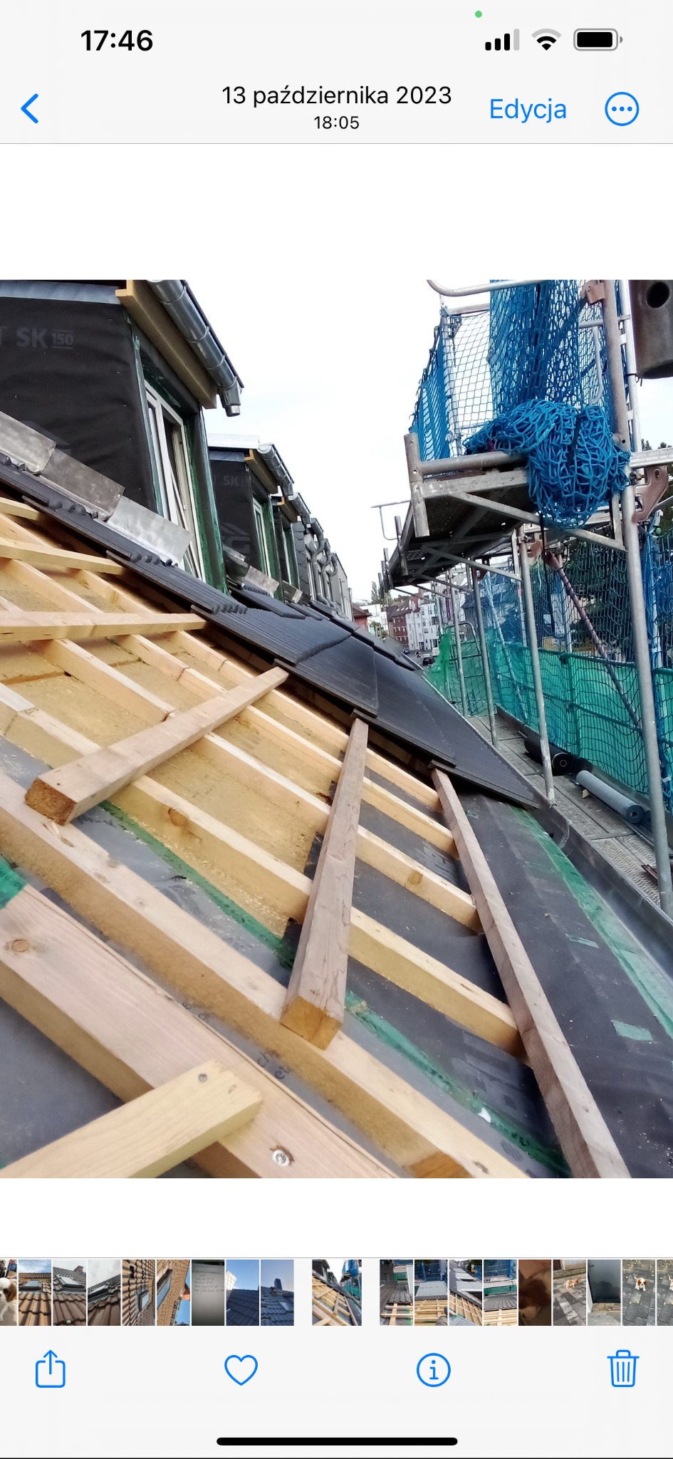 Montaż łat drewnianych na dachu z czarną membraną i częściowo ułożoną dachówką w zabudowie miejskiej, widoczne rusztowania.