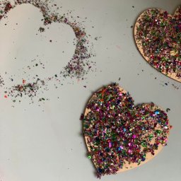 Nasze Maluchy (klub dziecięcy )placówka dwujęzyczna dla dzieci od 1 roku wzwyż -(angielsko -poski program) - Dwa drewniane serca pokryte kolorowym brokatem, obok serce z brokatu rozsypanego na szarym tle. Praca plastyczna w żłobku.