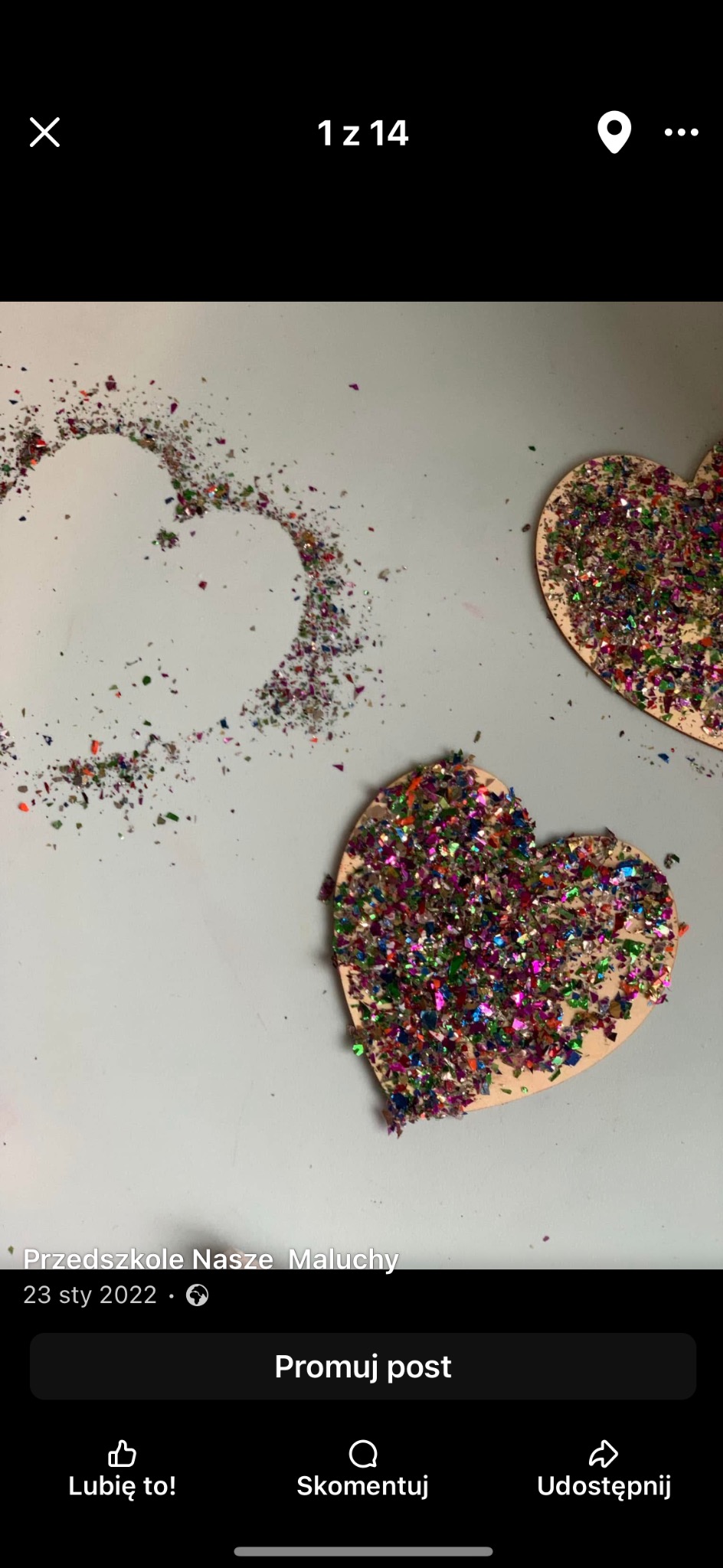 Dwa drewniane serca pokryte kolorowym brokatem, obok serce z brokatu rozsypanego na szarym tle. Praca plastyczna w żłobku.