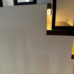 ArtSpawDesign MIODEK Marek Borowczak - Fragment nowoczesnego, minimalistycznego ogrodzenia z białych paneli z podświetleniem LED i elementami w kolorze ciemnego drewna.