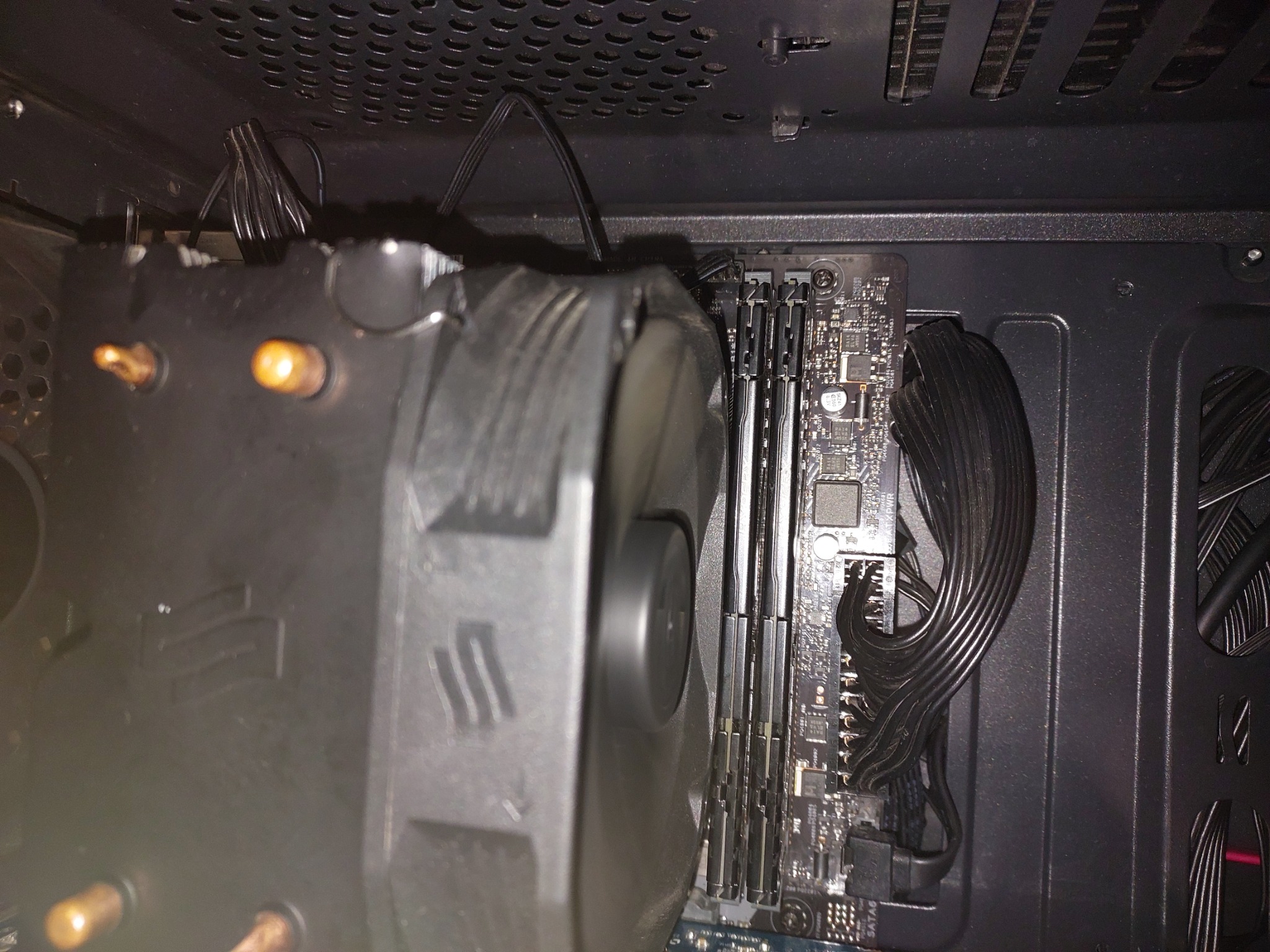 Wnętrze obudowy komputera z zamontowanym dużym radiatorem procesora z wentylatorem, widoczne kości pamięci RAM i uporządkowane kable zasilające.