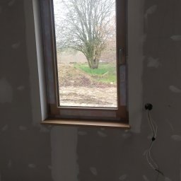 Stanislav Vorontsov - Ściana z oknem po nałożeniu gładzi, widoczne niedoskonałości i kable wystające ze ściany, profile metalowe na podłodze.