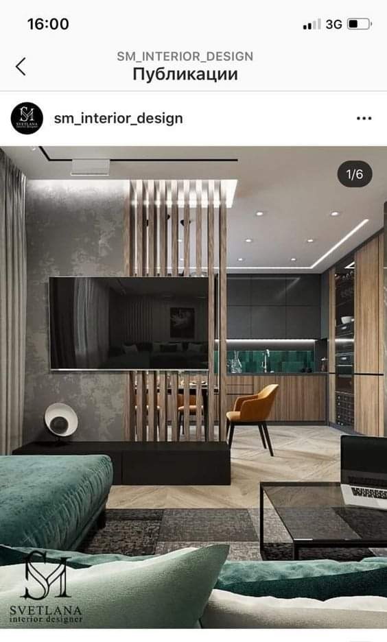 Nowoczesny salon z drewnianą ścianką działową, telewizorem, zieloną sofą i otwartą kuchnią w tle.