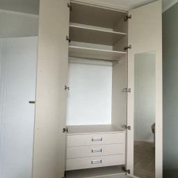 Fabis Meble na Wymiar - Otwarta, beżowa szafa z trzema szufladami, półkami i drążkiem na wieszaki; jedna z drzwi wyposażona w lustro.