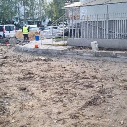 Ivan Polianskyi - Układanie obrzeży chodnikowych z betonu, widoczny pracownik w kamizelce odblaskowej i teren przygotowany pod dalsze prace. Prace ziemne w toku.