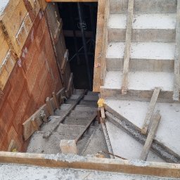 Ivan Polianskyi - Betonowe schody w trakcie budowy z drewnianym szalunkiem, widok z góry. W tle widoczne rusztowania i elementy konstrukcyjne.