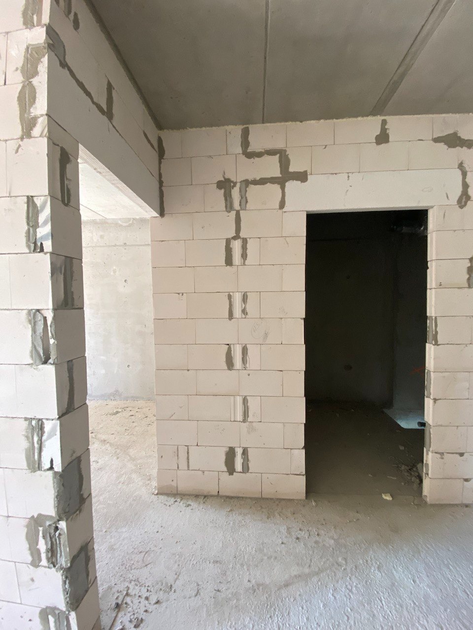 Wrocław: Wnętrze w trakcie budowy z widocznymi ścianami wzniesionymi z białych bloczków, świeżo połączonych zaprawą, surowy betonowy strop, widoczne otwory drzwiowe.