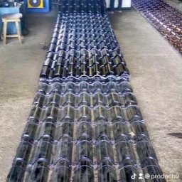 Robert ianek - Produkcja ciemnych dachówek ceramicznych na linii produkcyjnej w fabryce, widoczny pracownik obsługujący maszynę.