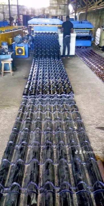 Produkcja ciemnych dachówek ceramicznych na linii produkcyjnej w fabryce, widoczny pracownik obsługujący maszynę.