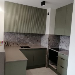 UPGRADE IVAN BOICHUK - Nowoczesna kuchnia w odcieniach szarości i oliwkowej zieleni z ryflowanym panelem ściennym, kamiennym blatem i czarną płytą grzewczą.