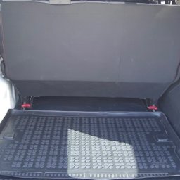 QRC Sławomir Dębinski - Wnętrze bagażnika białego samochodu dostawczego z rozłożonymi tylnymi siedzeniami i gumową wycieraczką podłogową z wzorem okręgów.