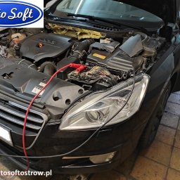 Auto Soft - Czarny samochód z otwartą maską, widoczny silnik z podłączonymi przewodami diagnostycznymi, otwarte drzwi po stronie kierowcy.