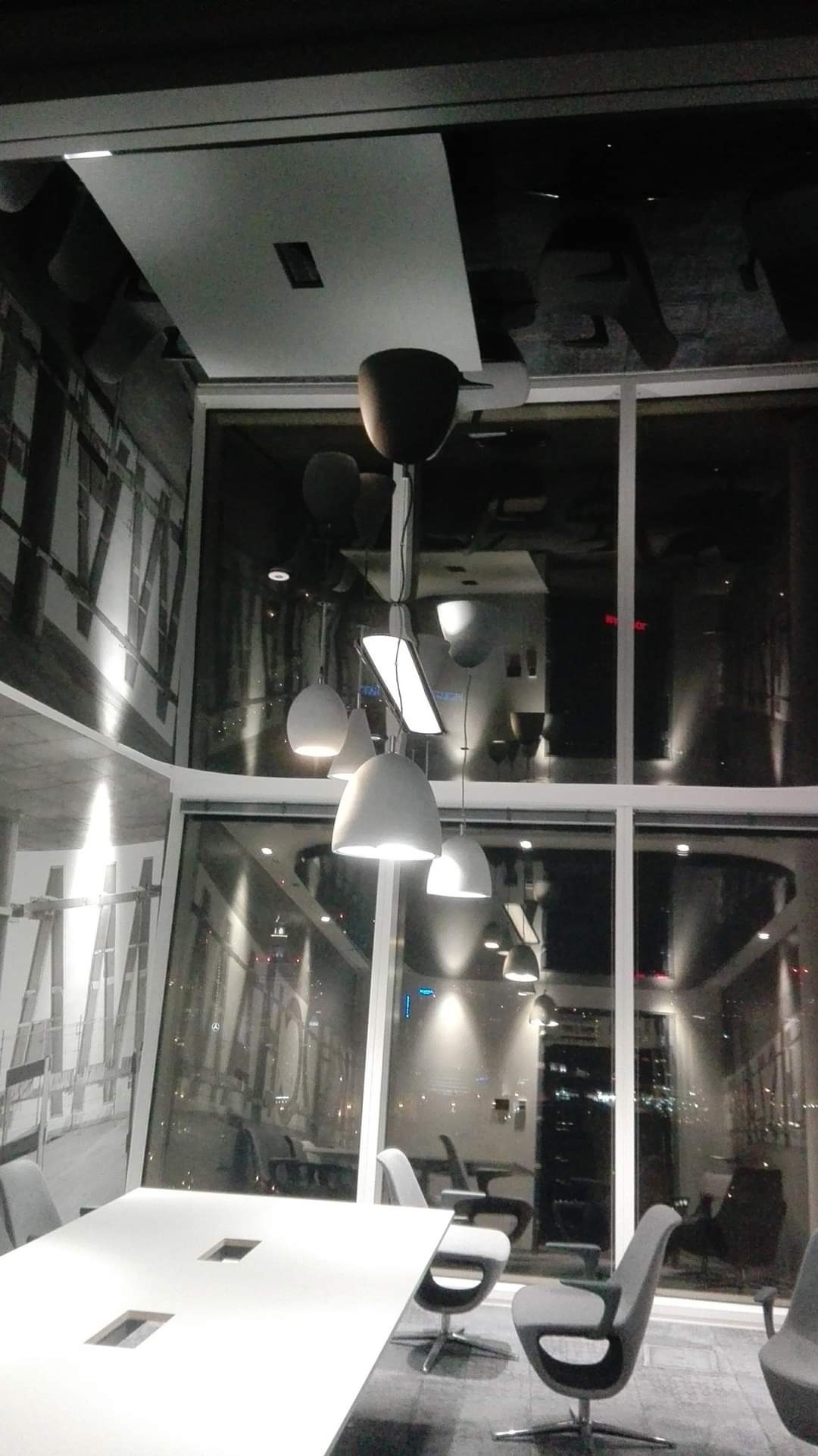 Nowoczesne oświetlenie sufitowe z lampami wiszącymi w sali konferencyjnej w Ciechanowie, widok na miasto przez duże okna.