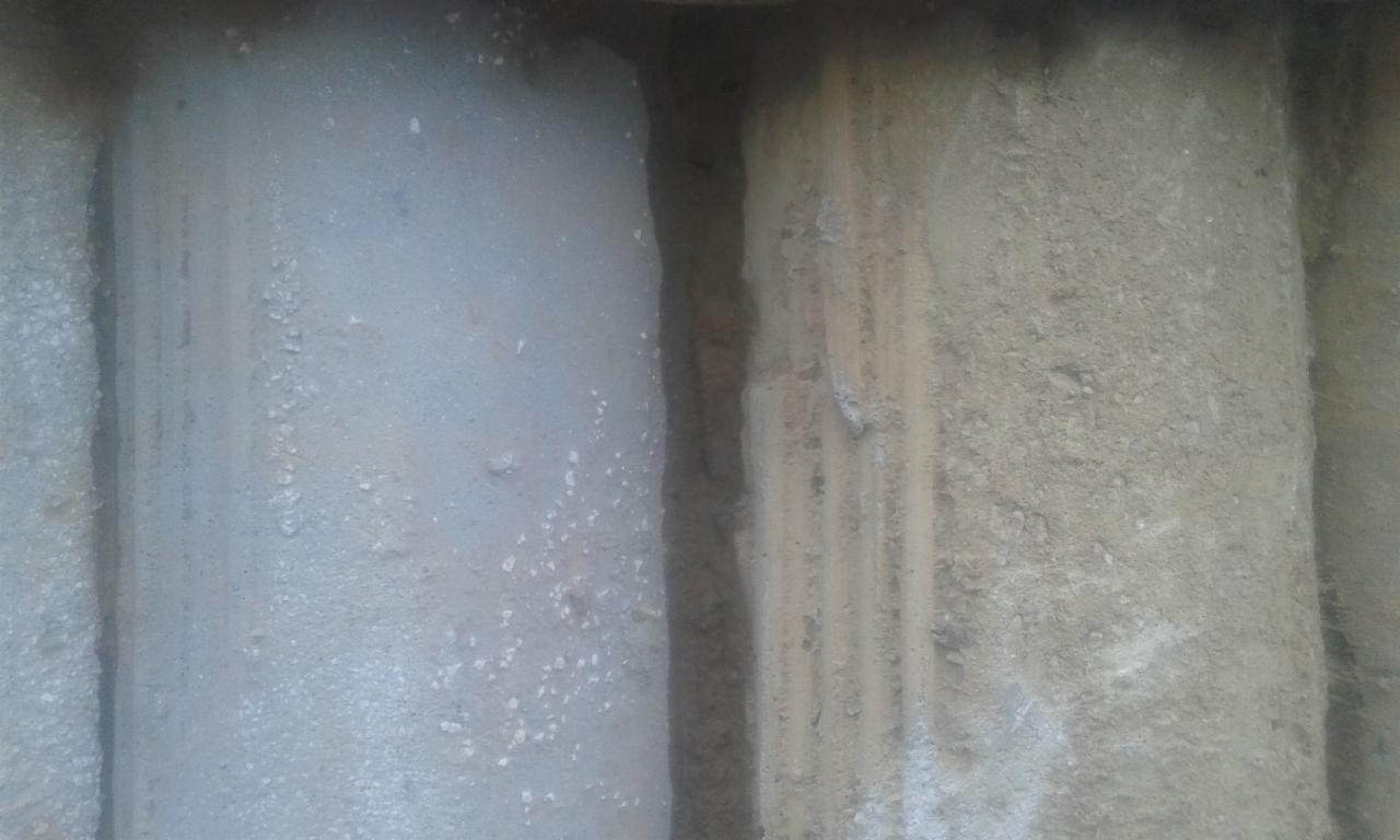 Betonowy element konstrukcyjny, częściowo oczyszczony, z widoczną różnicą w fakturze powierzchni przed i po obróbce.