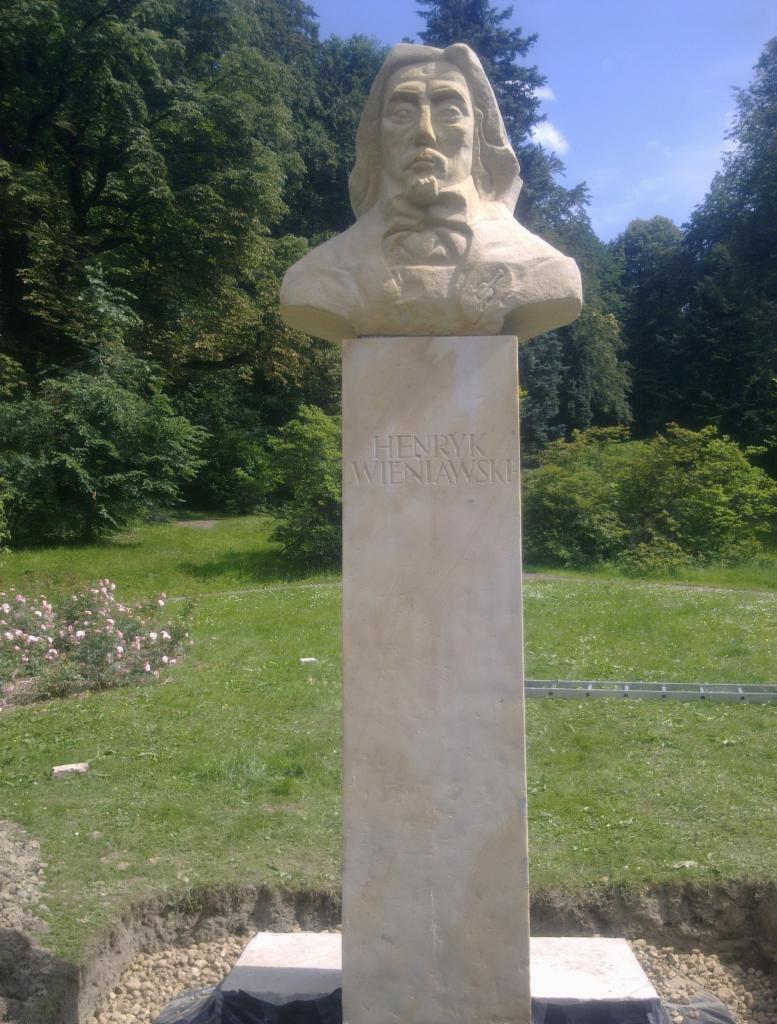 Pomnik Henryka Wieniawskiego w parku, z widocznym wykopem wokół podstawy, sugerującym prace instalacyjne lub renowacyjne.